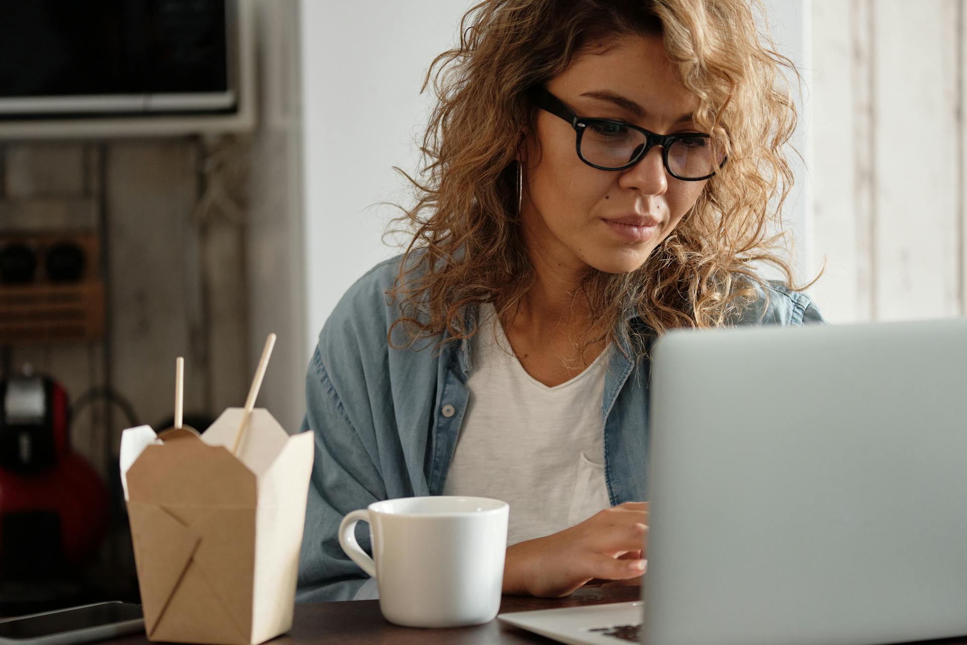 Small business owner at a café table researching how to choose a website builder on her laptop
